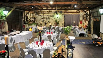 Rustic event barn with wooden beams, elegantly set tables for wedding reception